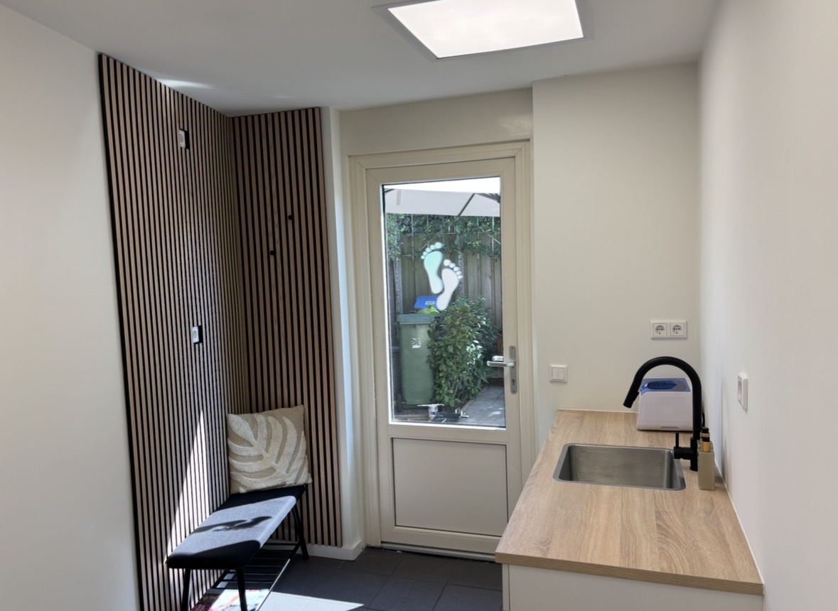 Praktijkruimte van Pedicure praktijk Melissa met houten lamellenwand en zithoek